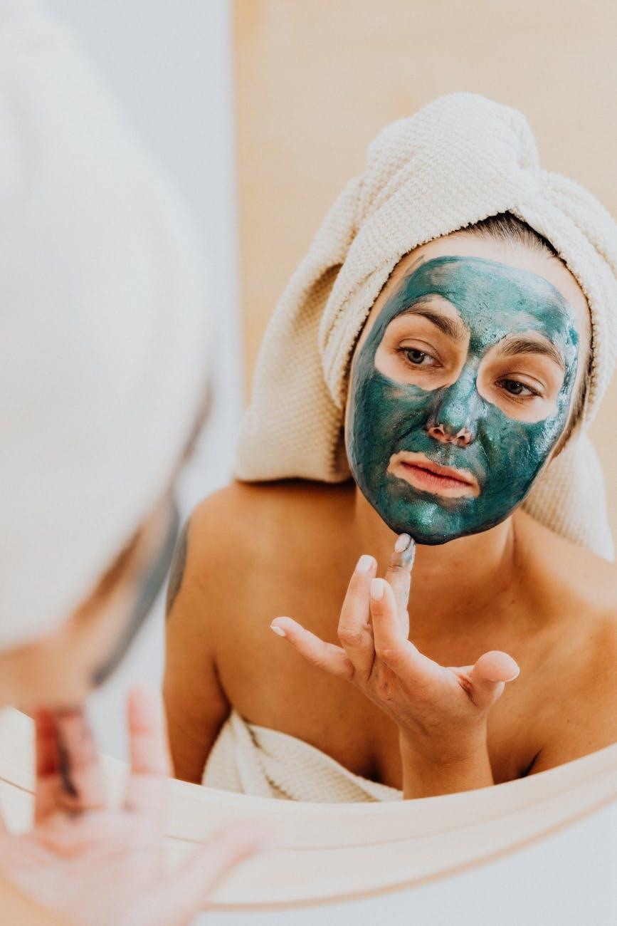 Woman applying a homemade clay face mask in a bathroom.
