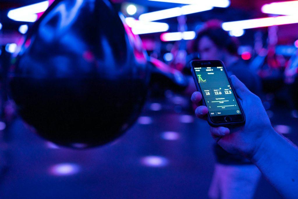 A smartphone displaying various fitness app icons like Peloton, MyFitnessPal, and Nike Training Club.